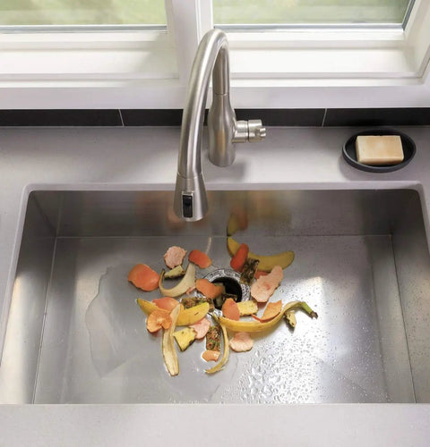 Kitchen sink with Disposall Garbage Disposal With Continuous Feed 0.5 HP Motor grinding food scraps, including meat and seeds.