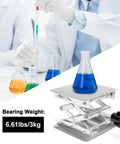 Stainless steel lab jack scissor stand with a 4x4-inch platform, supporting a blue liquid beaker.