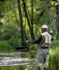 Angler casting in a lush forest stream with a 9Ft 5Wt Fly Fishing Rod Combo Starter Kit With 4 Piece Carbon Fiber Rod Semi Gloss Green Jade Finish.