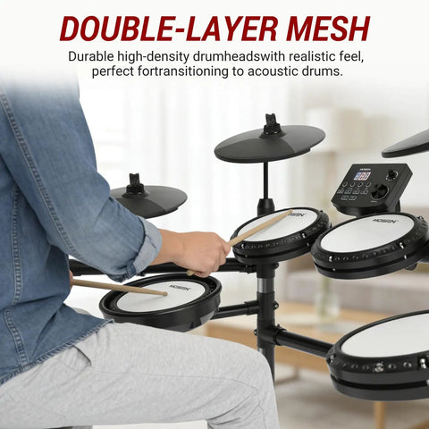 Person playing electric drum set with quiet mesh pads and cymbals, featuring USB MIDI and headphones for home practice.