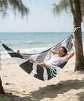 Zebra Inspired Camping Hammock With Tree Straps And Travel Bag Easy Setup No Knot Straps Ultra Thickened Durable 500 Pound Capacity Portable Single Hammock For Outdoor Camping Backyard Patio And Indoor Use hanging between trees on a beach, occupied by a man relaxing.