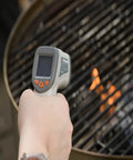 Person using No Touch Infrared Thermometer For Cooking And BBQ Laser Temperature Gun With Digital Display on grill