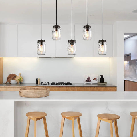 Five Light Mason Jar Chandelier with Rustic Glass Shades for kitchen island in a modern kitchen setting with wooden stools.