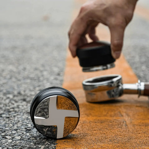 58mm Coffee Distributor And Espresso Leveler With Adjustable Height Stainless Steel Wedge Base next to a portafilter on pavement