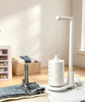 Large Thread Spool Stand For Sewing Machines with pink thread, hanging above a sewing machine on denim fabric.