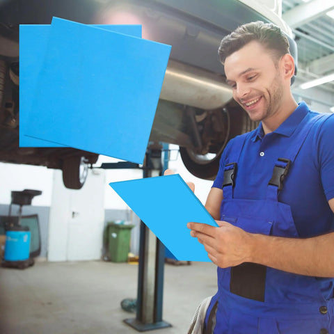 6 blue 8x8 inch non-asbestos gasket sheets, high-temperature gasket material, held by a mechanic under a car