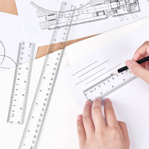 Hands using 6-inch clear plastic ruler with dual scales, part of Clear Plastic Ruler 6 Inch Plus 12 Inch set, on paper drawing.