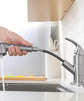 Slick Pullout Kitchen Faucet With Brushed Nickel Stainless Steel Single Handle Compact Design And Dual Spray Modes showing hand using spray head.