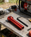 Close-up of red steel coupling sleeve with threaded end on a dusty workbench beside an L-shaped hex key