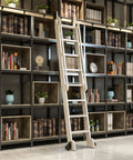 Interior library with a black shelf, books, decor, and a wooden ladder on wheels; ladder is part of customizable sliding system.