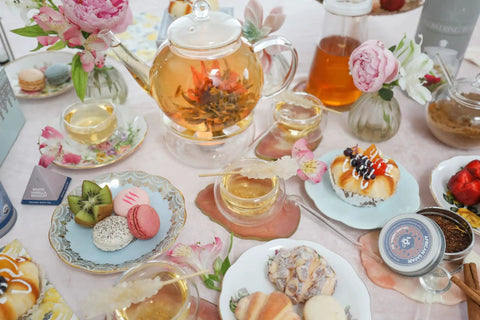 Stovetop And Microwave Safe Glass Teapot With Removable Infuser on a table with blooming teas and pastries, 34 oz borosilicate glass