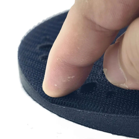 Close-up of a Durable Multi-Hole Sanding Buffer Pad 5.9 Inch showing finger pressing on sponge interface disc.