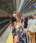 Person in subway wearing KN95 Face Mask Five Layer Cup Shaped Respirator With Breathable Comfort And High Filtration For Daily Dust And Pollutants
