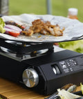Portable Butane Gas Stove With Carrying Case For Outdoor Cooking Electric Ignition Precise Heat Control Great For Camping Hiking RV Trips Tailgating Patio Grilling And Emergency Use cooking meat and vegetables on a table