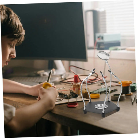 Helping Hands Soldering Tool With LED Magnifying Lamp And Adjustable Arms in use for electronics repair on a desk