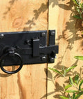 Heavy Duty Black Iron Gate Latch With Elegant Floral Base Plate And Weatherproof Coating Tough As Nails Two Sided Door Hardware For Outdoor Fences And Garden Gates mounted on wooden door.