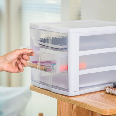Hand opening a drawer of the 4 Pack 3 Drawer Stackable Plastic Organizer With Drawers White Frame Go To Countertop Storage Solution For Office Supplies Craft Rooms Classrooms And Home Organization placed on a desk.