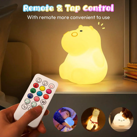 Remote control beside glowing Kids Night Light With Remote, 7 Color Kawaii Cat Nursery Lamp on a nightstand.