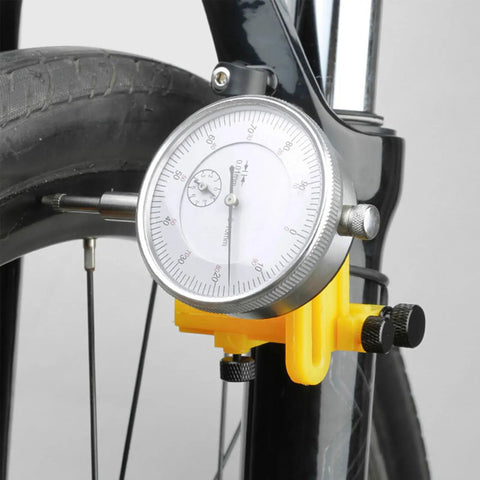 Close-up of Pro Grade Wheel Turning Stand With Dial Indicator for precise bike wheel alignment and repair at home, black.