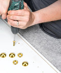 Person using a drill to secure Pure Brass Decorative Screw Covers With Smooth Caps Heavy Duty Self Tapping Bolts for Furniture And Mirror Repairs.