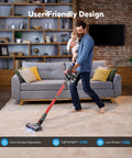 Cordless stick vacuum cleaner, front view, red, in use on living room carpet.