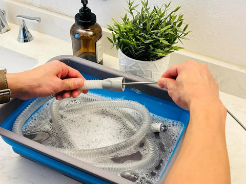 Hands using Hose And Mask Cleaning Kit With Extra Thick 6.9 Foot Tubing Brush in collapsible wash basin with CPAP hose