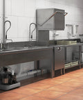 Sanicom 2 Commercial Wastewater Drain Pump under stainless steel sinks in a commercial kitchen setting.