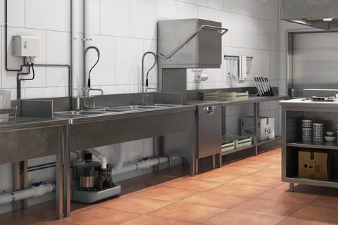 Sanicom 2 Commercial Wastewater Drain Pump under stainless steel sinks in a commercial kitchen setting.