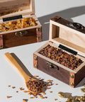 Two small wooden boxes filled with granules and a wooden spoon on a white surface