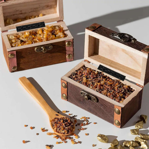 Two small wooden boxes filled with granules and a wooden spoon on a white surface