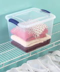 27 Quart Medium Clear Plastic Storage Bin With Heavy Duty Latching Lid And Sturdy Handles For Garage And Closet Organization holding stacked clothes on a shelf.