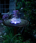 Solar Fountain Pump With Battery Power 4W Bird Bath Kit, 7 Nozzles, 30 LED Star Lights illuminating a garden bird bath at night