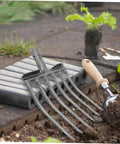 Heavy Duty Steel Fork Head For Soil Turning And Loosening with easy mount handle next to a garden trowel on soil.