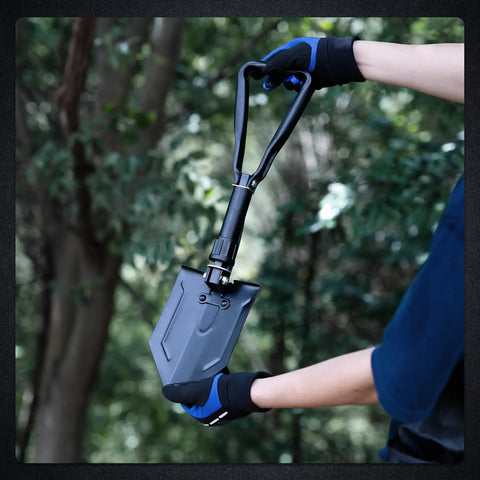 Person holding Beast Survival Folding Camp Shovel With Pickaxe Tri Fold Tactical Entrenching Tool in forest