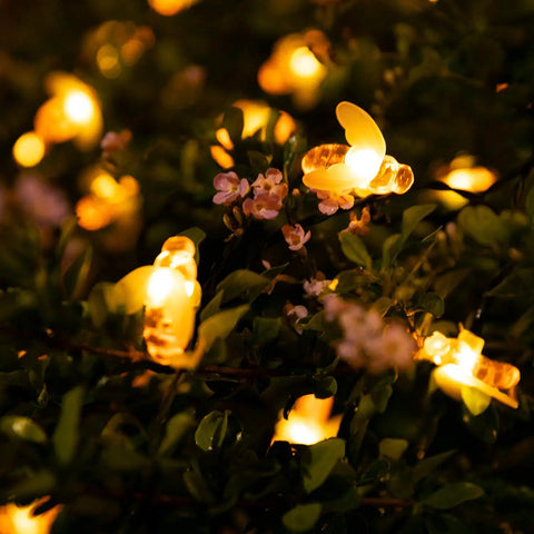 Solar Bee String Lights Outdoor 31Ft 50 LED Honeybee Fairy Lights With 8 Modes Waterproof Decor glowing on bushes.