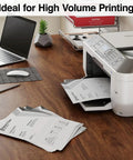 Premium White Copy And Printer Paper 8.5 X 11 Inches Twenty Pound Weight in use with a laser printer on a desk.