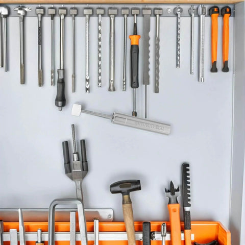 Various tools including a hammer, wrenches, and screwdrivers organized on a wall panel, showcasing a tool storage setup.