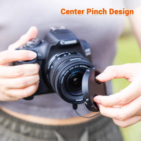 Person placing Two Pack 58mm Front Lens Cap With Center Pinch And Universal Lens Cap Keeper on DSLR camera outdoors