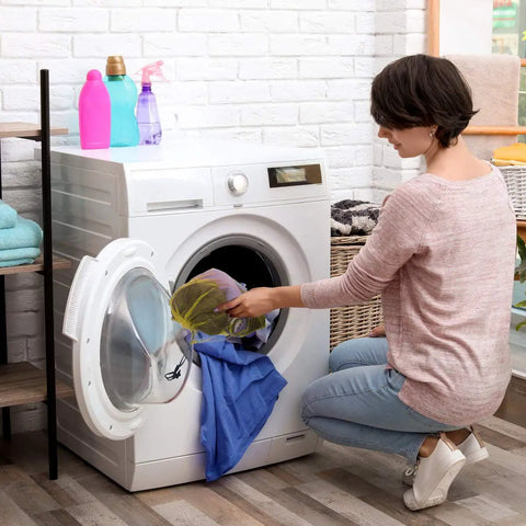 Woman sorting laundry using 12 Pack Tough Nylon Mesh Drawstring Bags 13 By 15.5 Inches With Cord Lock Closure in yellow.