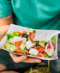 Person holding salad in Heavy Duty Red Disposable Food Trays 3lb Capacity Workhorse Bulk Pack 250 Count For Concession Stands.