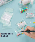 Person writing on Travel Pill Bags Pouch Organizer 240 Pack BPA Free Reusable Pouches With Writable Labels, pills visible.