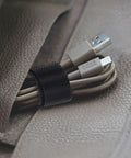 Reusable Cable Ties Organizer Set For Home Office And Tech Gear, black strap securing USB cables on textured surface