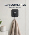 Heavy Duty Black Adhesive Wall Hooks Peel And Stick Hangers No Mess Quick Install For Entryway Keeps Counters Clear holding a towel on a bathroom wall.