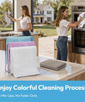 Front view: Six-pack microfiber cleaning cloths, 12x12, white with blue and purple accents on a metal rack in a kitchen.