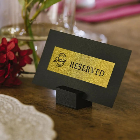 Black reserved sign with gold label on a wooden table, labeled using P-Touch CUBE Plus Bluetooth Label Maker PT-P710BT.