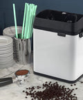 Electric Portafilter Cleaning Station And Knock Box For No Sweat Espresso Ground Disposal Straight Up Fast Dump Mechanism displayed beside coffee grounds.