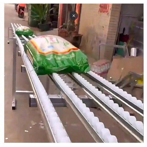 Light Duty Roller Skate Slide Track For Beverage Barrel Transport With Abs Plastic Rollers And Light Stainless Steel Frame moving a green packaged bag.