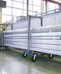 Heavy Duty Cast Iron Caster Wheels With Polyurethane Tread And Half Inch Bore Roller Bearing on a rolling cart in a warehouse setting.