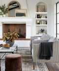 Modern living room with fireplace, cozy seating, bookshelves, and decorative plants.