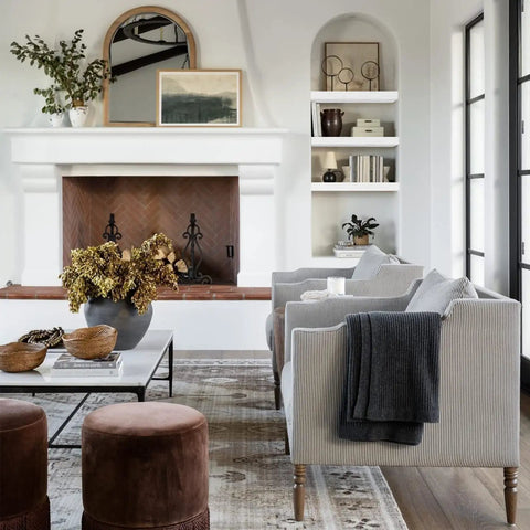 Modern living room with fireplace, cozy seating, bookshelves, and decorative plants.